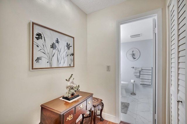 hall featuring visible vents, marble finish floor, and baseboards