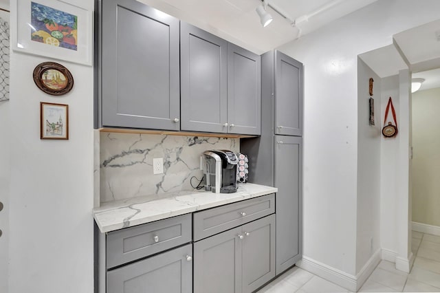 bar featuring tasteful backsplash, light tile patterned floors, rail lighting, and baseboards