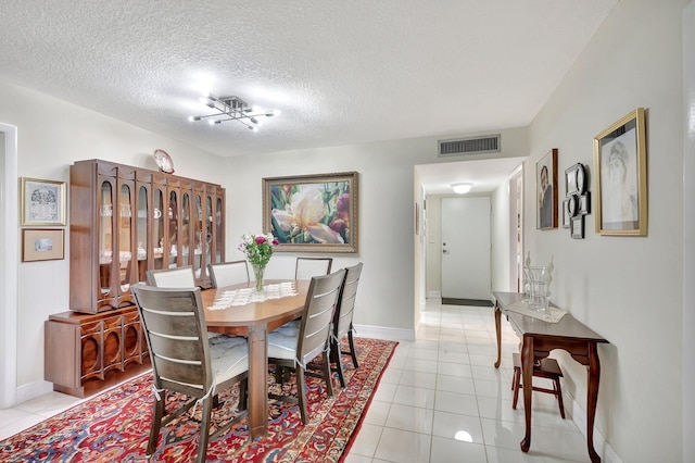 dining area with light tile patterned floors, visible vents, and a textured ceiling