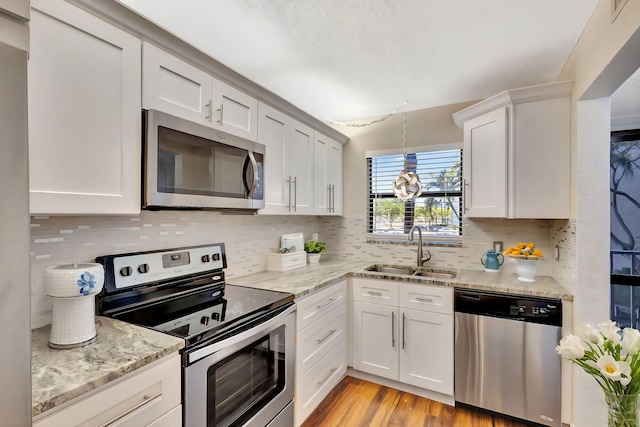 kitchen featuring decorative backsplash, light wood-style flooring, appliances with stainless steel finishes, and a sink