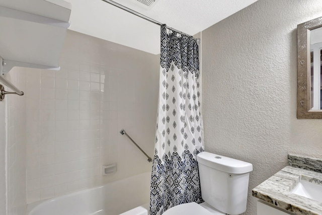 bathroom with vanity, toilet, a textured wall, and shower / bath combo