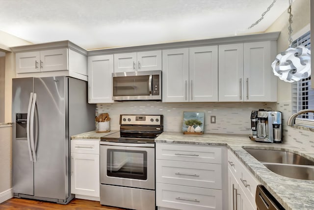 kitchen with light stone countertops, tasteful backsplash, appliances with stainless steel finishes, and a sink