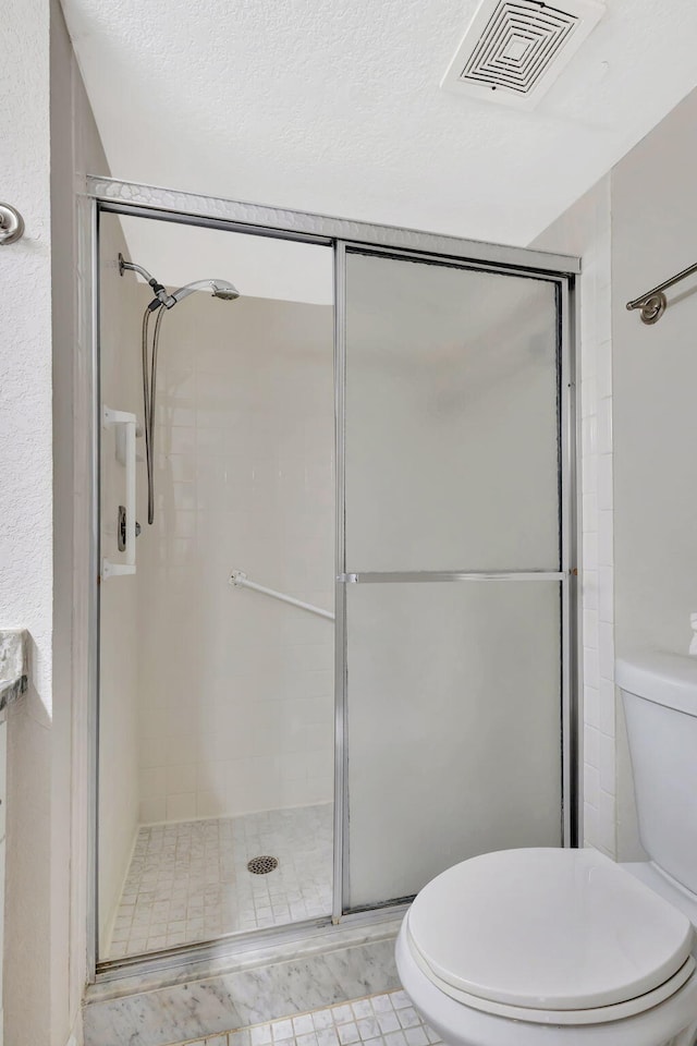 full bathroom featuring a shower stall, toilet, and visible vents