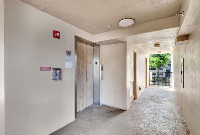 hallway featuring elevator and concrete flooring