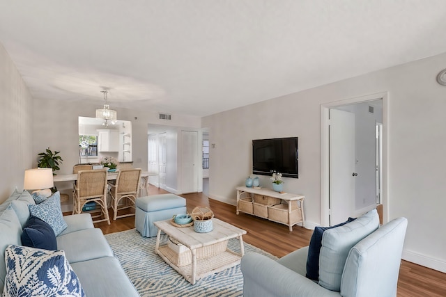 living room with visible vents, baseboards, and wood finished floors