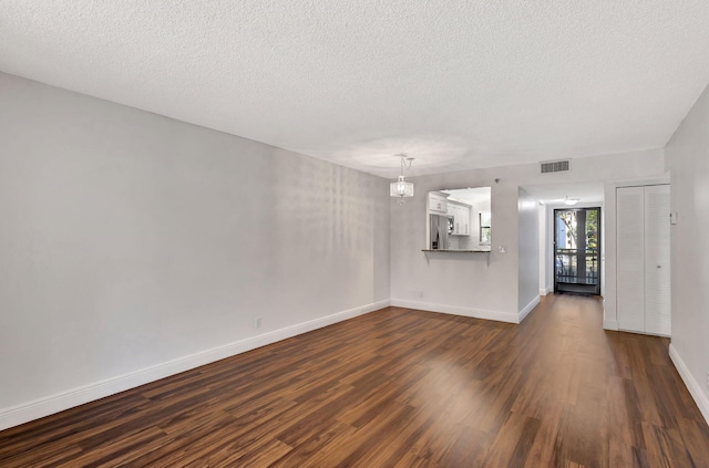 unfurnished living room with a textured ceiling, dark wood-style floors, visible vents, and baseboards