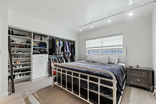 bedroom featuring wood finish floors, a closet, and track lighting