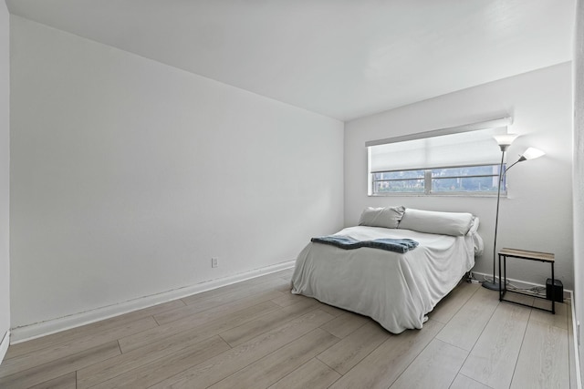 bedroom featuring baseboards and light wood finished floors