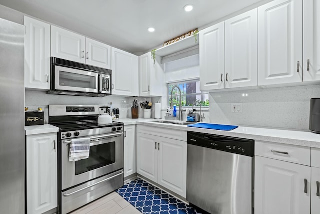 kitchen featuring a sink, stainless steel appliances, white cabinets, and light countertops