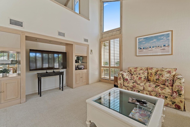 carpeted living area featuring visible vents and a towering ceiling