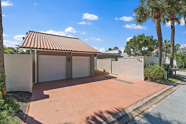 garage featuring a gate, fence, and driveway