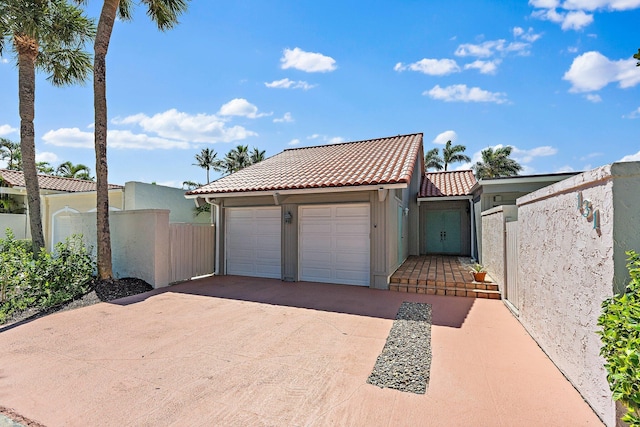 view of front of property featuring fence, concrete driveway, a tile roof, stucco siding, and a garage