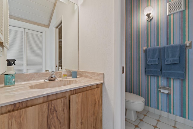 bathroom featuring tile patterned floors, toilet, wallpapered walls, baseboards, and vanity