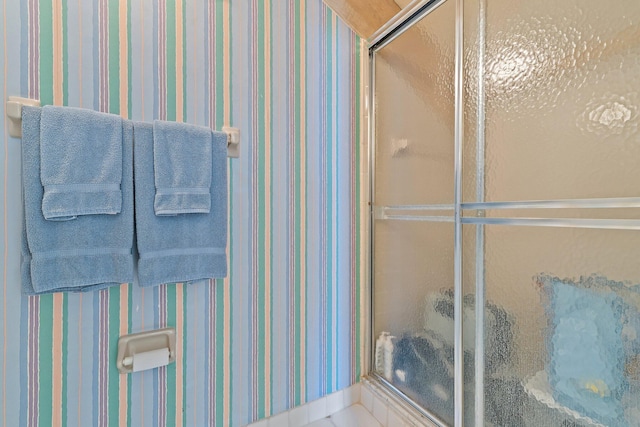 bathroom with wallpapered walls and a stall shower