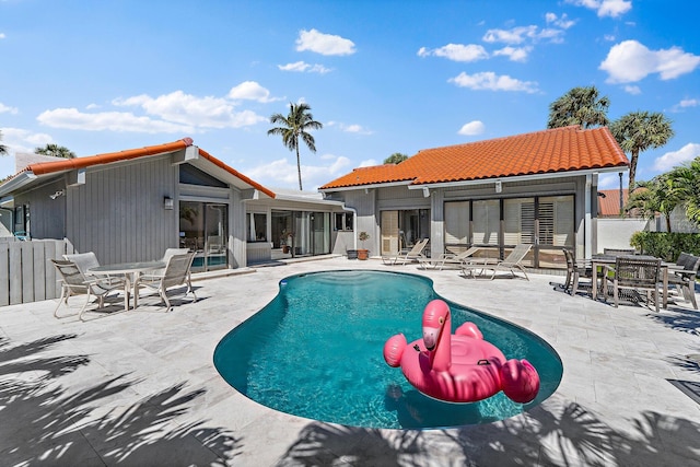 pool with a patio, fence, and a sunroom