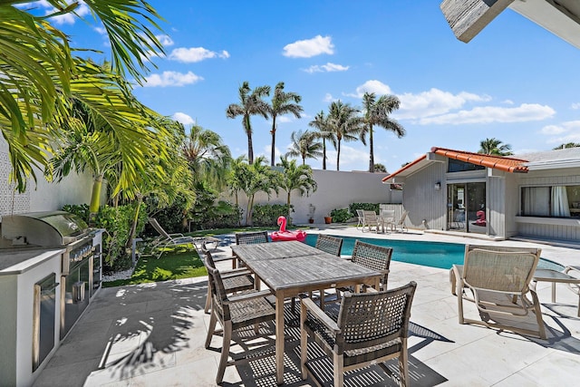 view of swimming pool featuring fence, outdoor dining area, an outdoor kitchen, a grill, and a patio