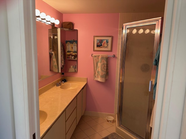 full bathroom featuring a stall shower, a sink, tile patterned flooring, double vanity, and baseboards