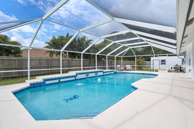 view of swimming pool featuring a fenced in pool, glass enclosure, an outdoor structure, a fenced backyard, and a patio area