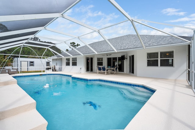 pool with glass enclosure, a ceiling fan, a patio, and fence