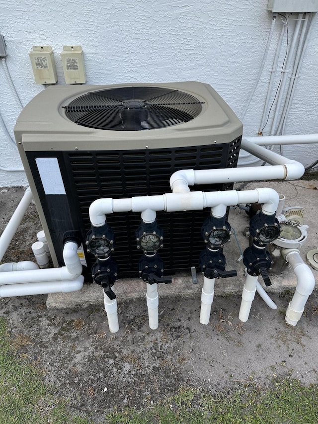details with central air condition unit, pump, and stucco siding