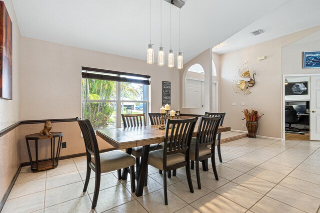 dining room featuring light tile patterned floors, visible vents, arched walkways, and baseboards