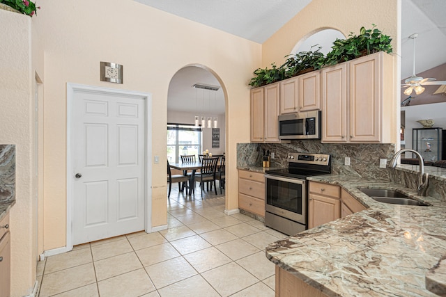 kitchen featuring a ceiling fan, light brown cabinetry, a sink, appliances with stainless steel finishes, and backsplash