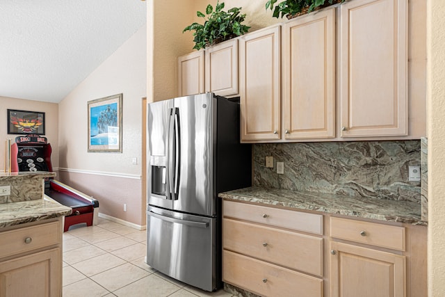 kitchen with decorative backsplash, vaulted ceiling, stainless steel refrigerator with ice dispenser, and light brown cabinetry