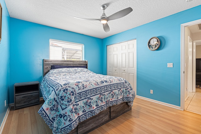 bedroom with baseboards, wood finished floors, a closet, and a textured ceiling