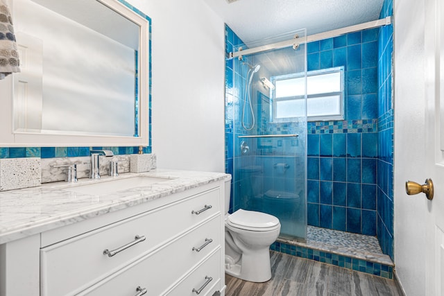 full bath featuring toilet, a stall shower, wood finished floors, a textured ceiling, and vanity