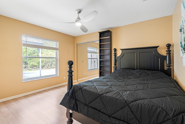 bedroom with ceiling fan, a textured ceiling, baseboards, and wood finished floors