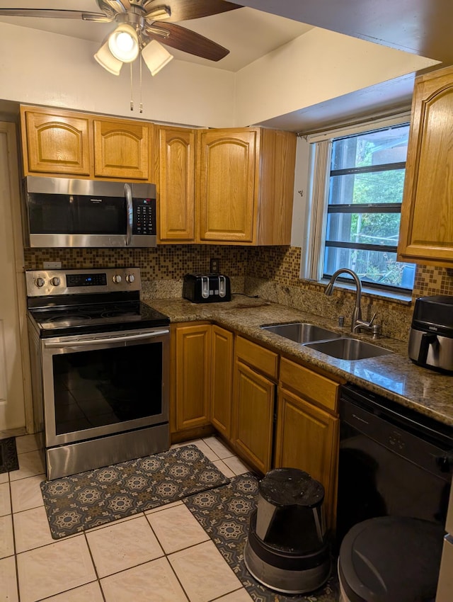 kitchen featuring light tile patterned floors, a sink, ceiling fan, stainless steel appliances, and backsplash