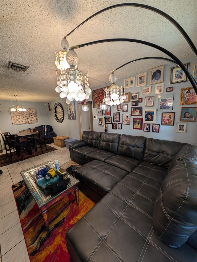 living area featuring tile patterned floors, visible vents, a textured ceiling, and an inviting chandelier