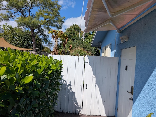 view of side of home with a gate, stucco siding, and fence