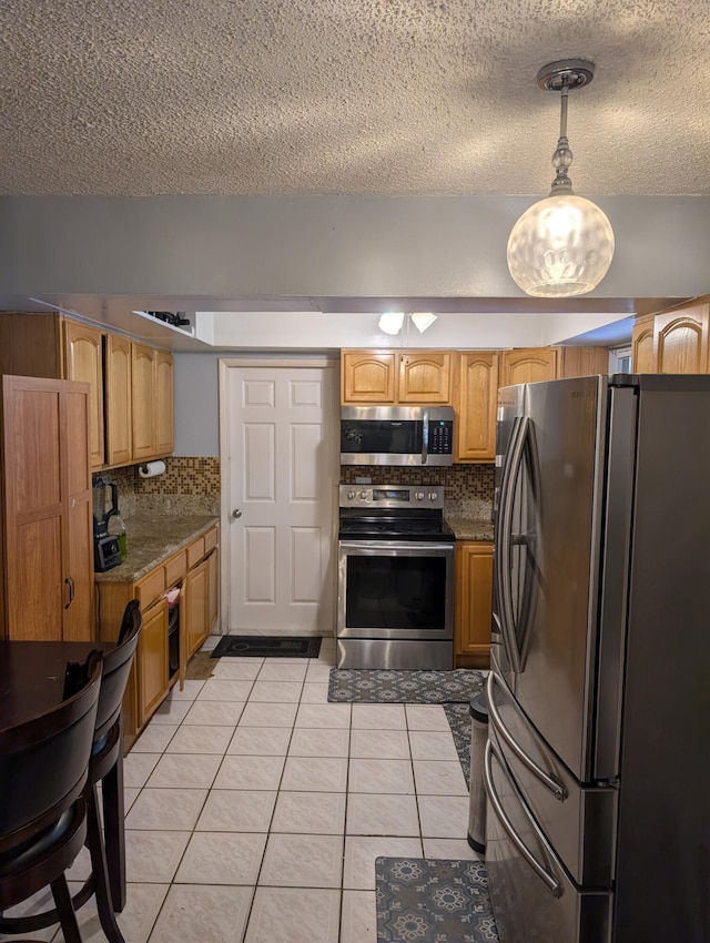 kitchen featuring pendant lighting, light tile patterned floors, decorative backsplash, appliances with stainless steel finishes, and a textured ceiling