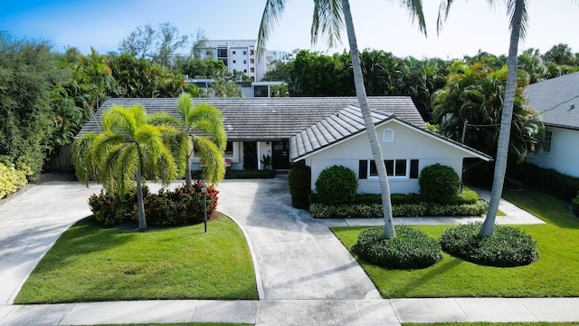 view of front of home with stucco siding, driveway, a tile roof, and a front lawn