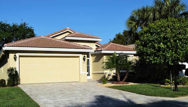 mediterranean / spanish-style house featuring stucco siding, a garage, driveway, and a tiled roof