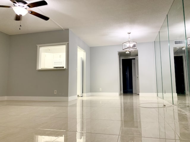 spare room with a ceiling fan, visible vents, baseboards, a textured ceiling, and marble finish floor