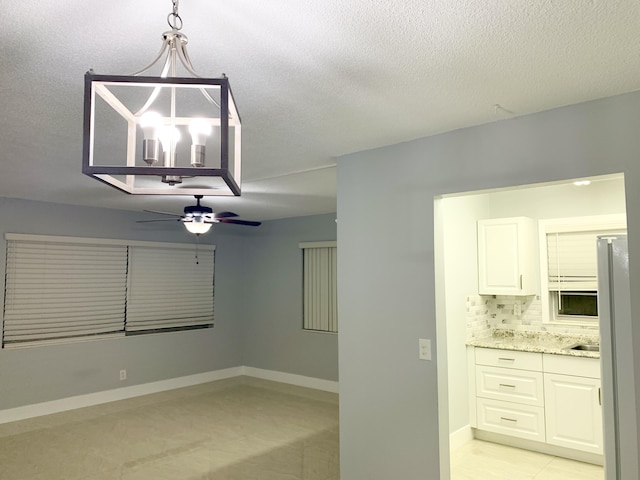 interior space featuring baseboards, a textured ceiling, and ceiling fan