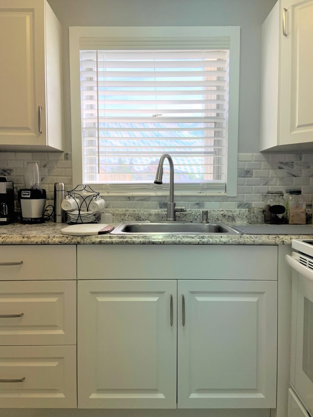 kitchen with a sink, decorative backsplash, plenty of natural light, and white cabinetry