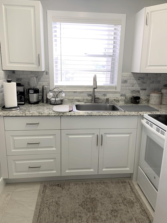 kitchen featuring decorative backsplash, white cabinets, white electric stove, and a sink