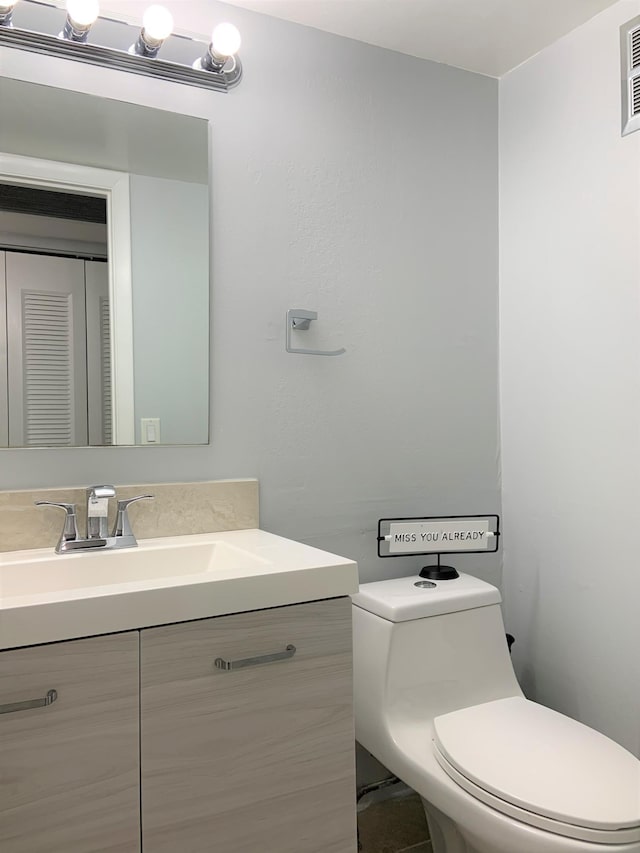 bathroom with vanity, toilet, and visible vents