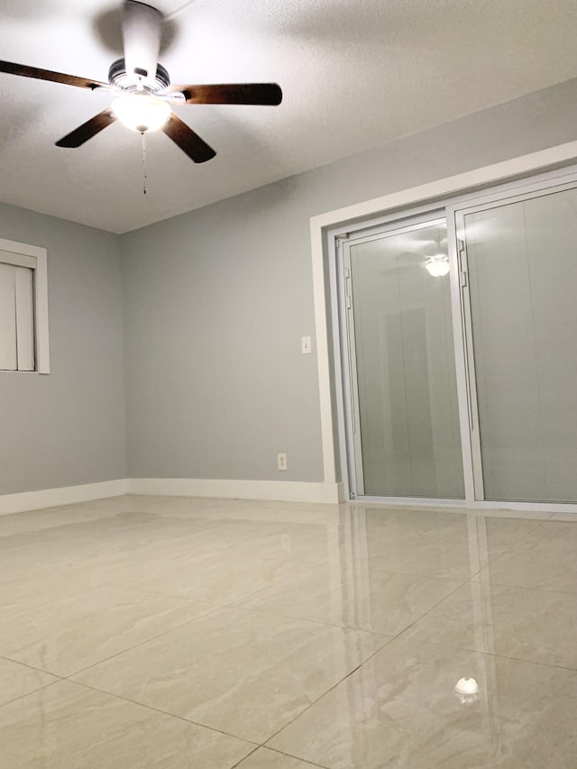 unfurnished bedroom featuring ceiling fan, a textured ceiling, and baseboards