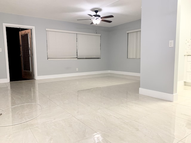 spare room featuring a ceiling fan, baseboards, and marble finish floor