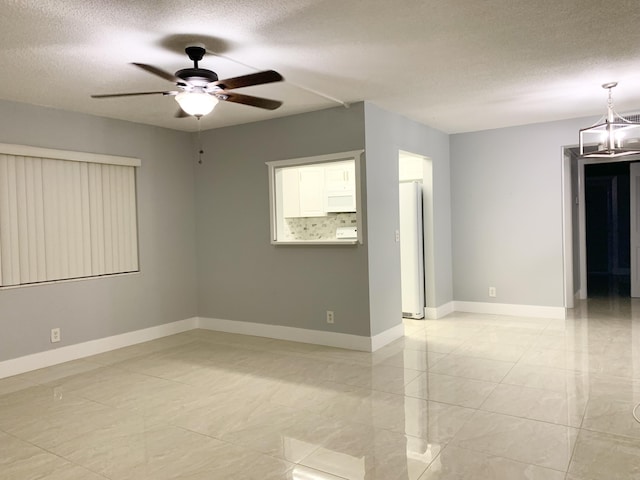 empty room featuring a ceiling fan, baseboards, and a textured ceiling