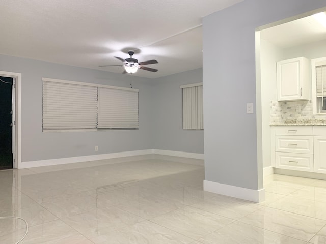 spare room with baseboards, marble finish floor, and ceiling fan