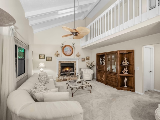 living room with a ceiling fan, baseboards, a stone fireplace, beamed ceiling, and carpet flooring