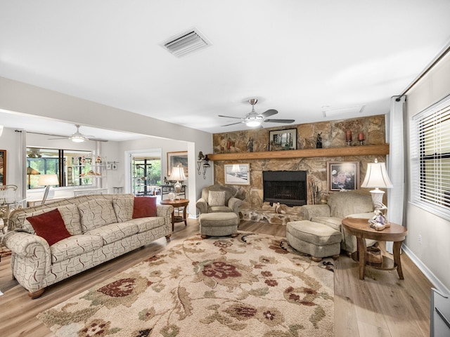 living room with visible vents, a fireplace, a ceiling fan, and wood finished floors