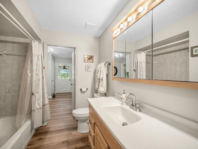 bathroom with toilet, wood finished floors, a textured ceiling, vanity, and shower / bathtub combination with curtain