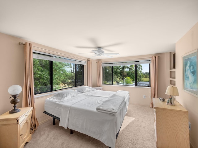 bedroom featuring light colored carpet, baseboards, and ceiling fan