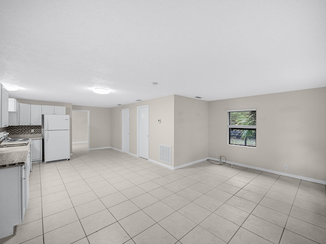 interior space featuring dark countertops, open floor plan, freestanding refrigerator, and visible vents